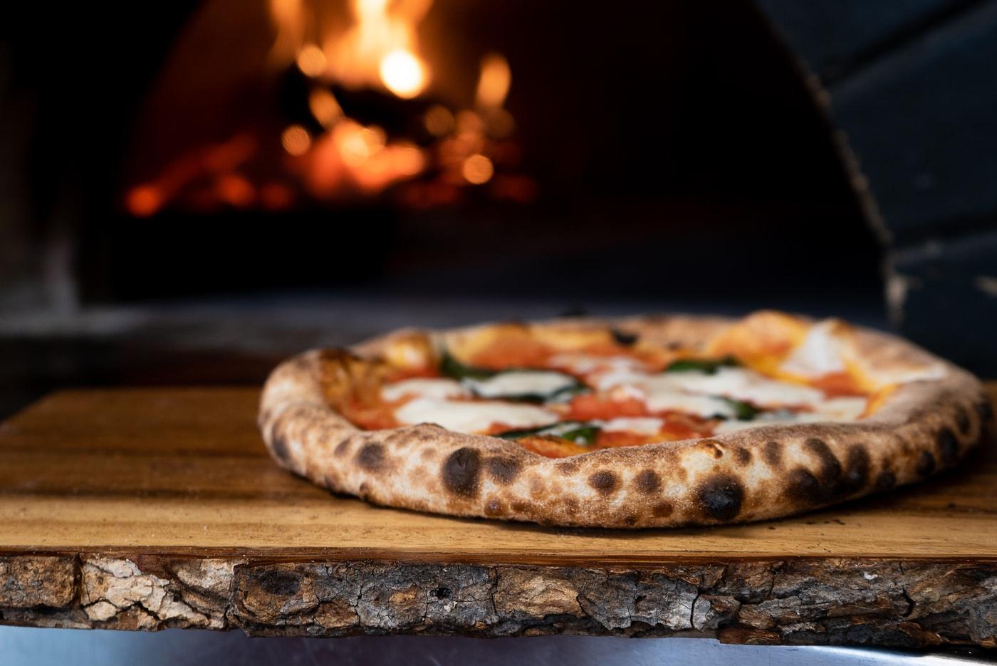 Pizza saliendo del horno a leña